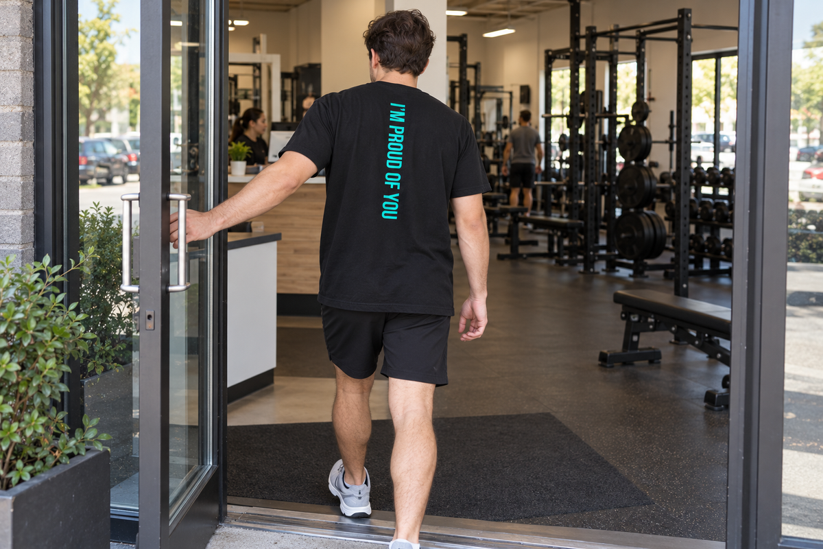 Man entering a gym in a black HM T-shirt with teal ‘I’m Proud of You’ lettering down the back.