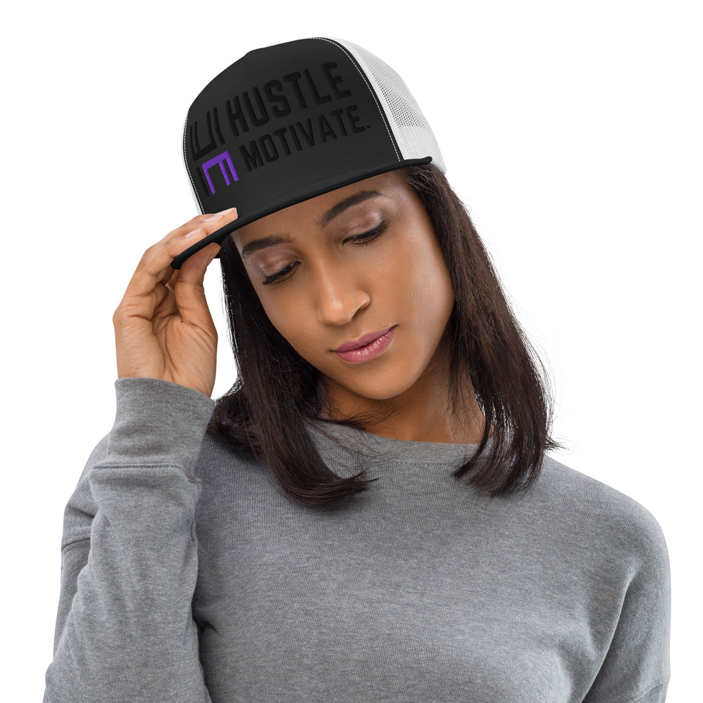 Model wearing the black and white Hustle Motivate Elevate trucker cap with black lettering, a purple HM accent and white mesh panels