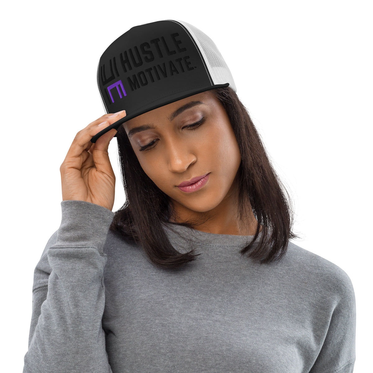Model wearing the black and white Hustle Motivate Elevate trucker cap with black lettering, a purple HM accent and white mesh panels