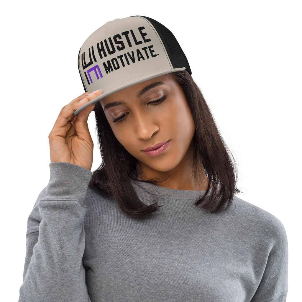 Model wearing the silver and black Hustle Motivate Elevate trucker cap with black lettering, a purple HM accent and black mesh panels