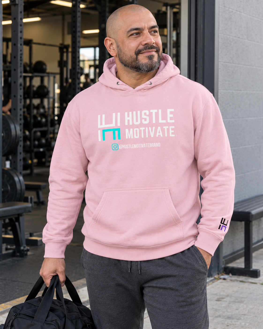 AI lifestyle mockup of the Light Pink Hustle Motivate hoodie worn outside a gym.