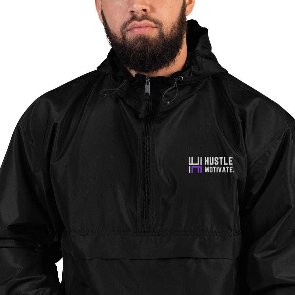 Close-up of a model wearing the black Hustle Motivate Packable Windbreaker, showing white and purple chest embroidery.