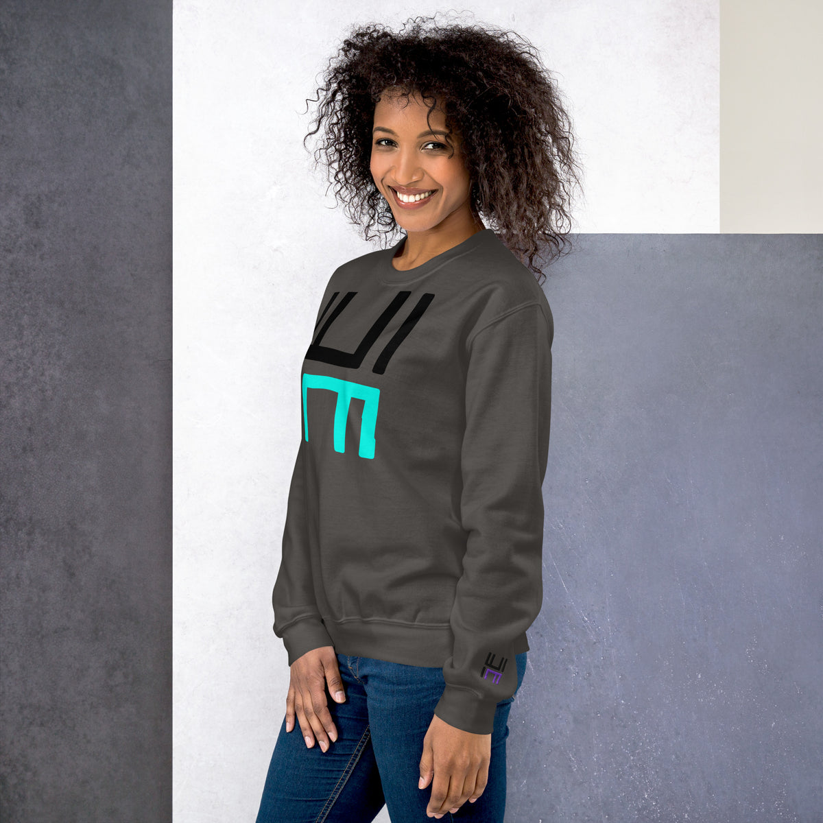 Model wearing the Hustle Motivate Statement Crewneck in charcoal, showing the front print and embroidered left sleeve
