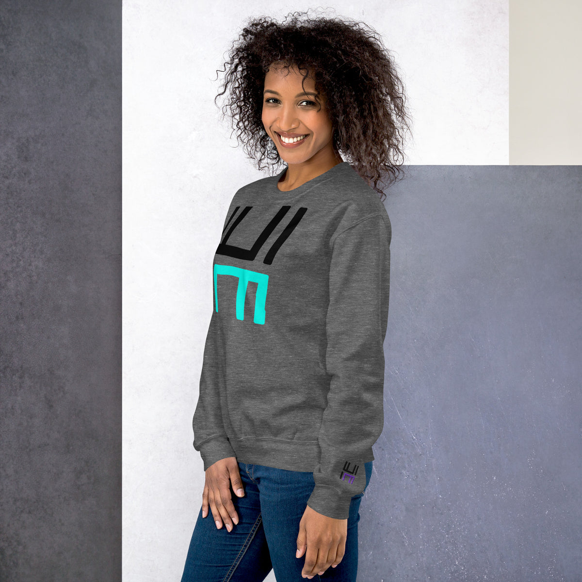 Model wearing the Hustle Motivate Statement Crewneck in graphite heather, showing the front print and embroidered left sleeve