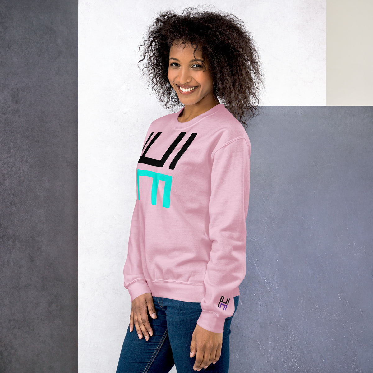 Model wearing the Hustle Motivate Statement Crewneck in light pink, showing the front print and embroidered left sleeve