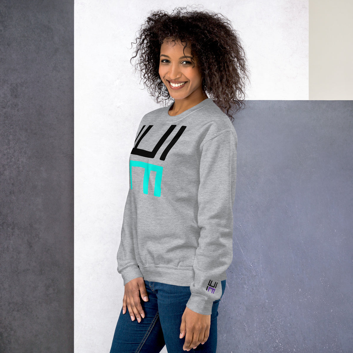 Model wearing the Hustle Motivate Statement Crewneck in sport grey, showing the front print and embroidered left sleeve